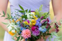 a bold bridesmaid wedding bouquet with purple, fuchsia, pink, yellow and blue blooms and greenery is pure fun