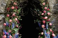 a bold floral wedding arch decorated with twigs, fern, delphinium and pink peonies look spectacular