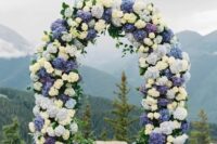 a bold floral wedding arch done with white, light blue and purple hydrangeas and foliage is a lovely and catchy wedding idea