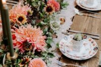 a bold monochromatic wedding tablescape with pink and orange dahlias, greenery and dark green candles, floral print plates and neutrla cutlery