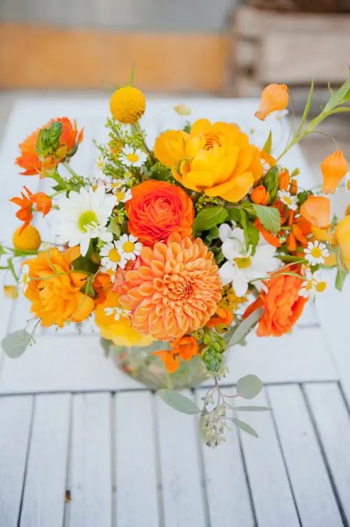 a bold orange wedding bouquet with orange dahlias, ranunculus, chamomiles, greenery is amazing for a rustic wedding