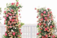 a bold wedding altar of greenery, pink and coral peonies, peachy and white roses is a gorgeous statement for a wedding