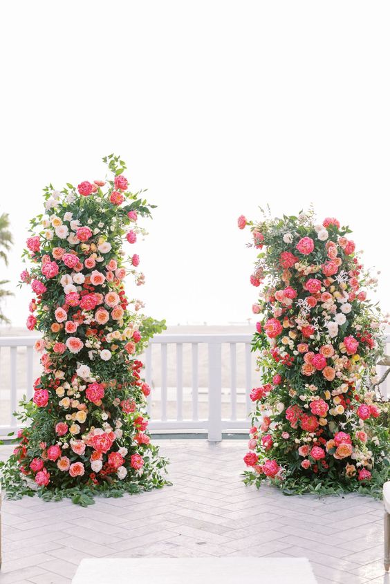 a bold wedding altar of greenery, pink and coral peonies, peachy and white roses is a gorgeous statement for a wedding