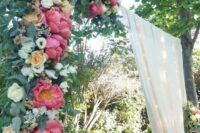 a bold wedding arch with sheer fabric, coral peonies, white and blush roses and greenery is a stylish idea for a wedding