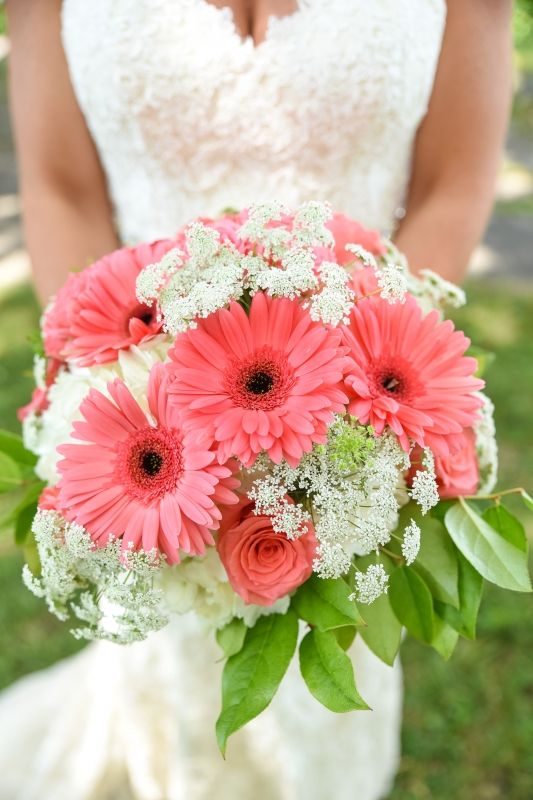 a bold wedding bouquet of coral gerberas and roses, some fillers and leaves is a catchy solution that makes a statement with color