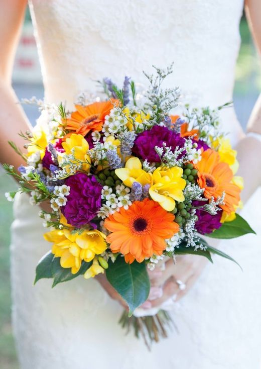 a bold wedding bouquet of orange gerberas, purple and yellow blooms, leaves and fillers is a cool idea for a bold wedding