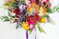 a bold wedding bouquet with yellow, burgundy, purple blooms, greenery, astilbe and purple ribbons is fun