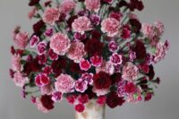 a bold wedding centerpiece of a tall urn with pink, fuchsia and burgundy carnations will be great for a Valentine’s Day wedding