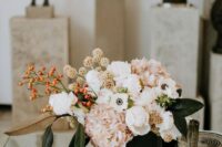 a bold wedding centerpiece of blush hydrangeas, white anemones and peonies, berries, leaves and seed pods for a modern wedding
