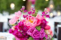 a bold wedding centerpiece of bright fuchsia blooms including carnations and peonies and some greenery is a lovely idea