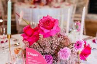 a bold wedding centerpiece of pink baby’s breath, hot pink roses and carnations and a pink menu next to it is a cool idea