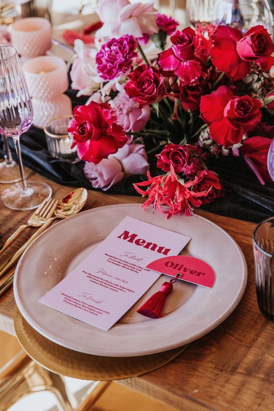 a bold wedding centerpiece of red and pink roses and hot pink carnations is a cool idea for a bright wedding