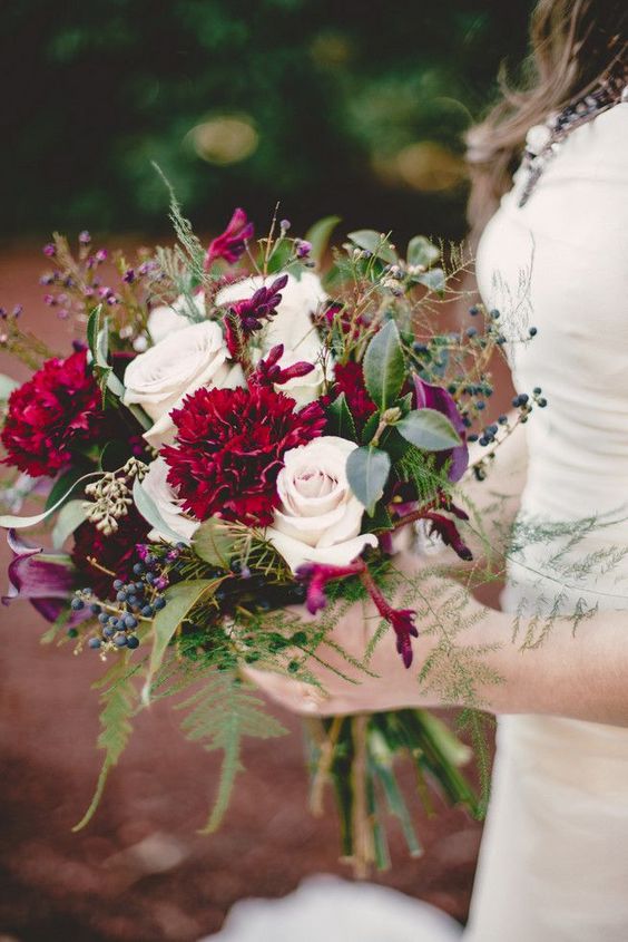 a bright and catchy wedding bouquet of blush roses and burgundy carnations and callas, textured greenery and leaves plus berries
