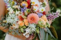 a bright and fun summer wedding bouquet of coral dahlias, yellow roses, white blooms, greenery, succulents, long ribbons is amazing