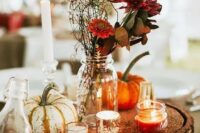 a bright and simple fall rustic wedding centerpiece of a wood slice with glitter, candles, pumpkins, burgundy blooms and greenery