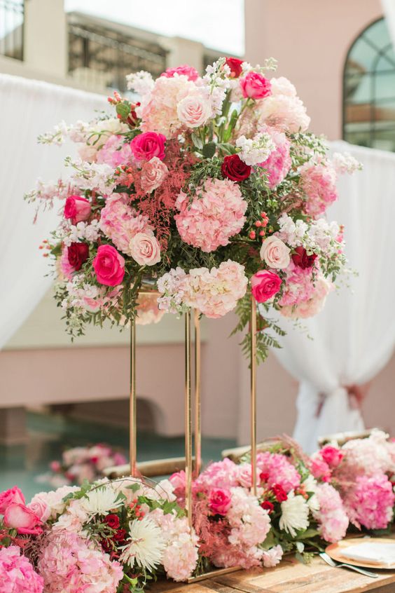 a bright and tall wedding centerpiece of pink hydrangeas and roses, blush, hot pink and burgundy roses and greenery