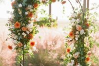 a bright fall wedding arch decorated with greenery, white and orange dahlias is a cool and chic idea
