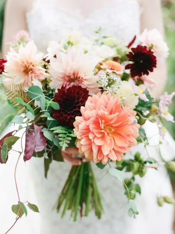 a bright fall wedding bouquet of burgundy, blush and orange dahlias, greenery and fern is a gorgeous idea