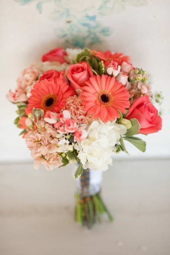 a bright rustic wedding bouquet of blush and white hydrangeas, coral gerberas and roses and some greenery for a bold wedding