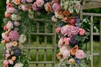 a bright wedding arch done with pink hydrangeas, roses and peony roses, purple hydrangeas, orange roses and greenery is wow
