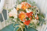 a bright wedding bouquet of orange gerberas and dahlias, white dahlias, greenery and berries plus some rope