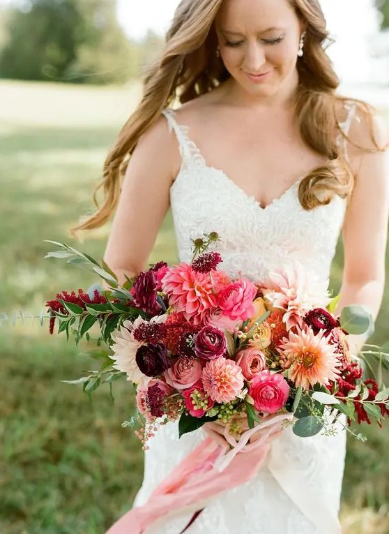 a bright wedding bouquet of pink and purple raunuculus and pink and white dahlias, greenery and pink ribbons for an accent