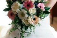 a bright wedding bouquet of white roses and gerberas, pale orange and pink gerberas, thistles and greenery for a summer wedding