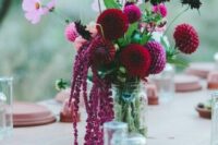 a bright wedding centerpiece of burgundy and purple dahlias, deep purple ones and some white and pink fillers plus lisianthus