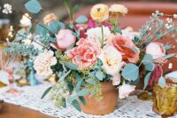 a bright wedding centerpiece of neutral and pastel blooms, carnations, peony roses and ranunculus, greenery and berries