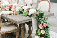 a bright wedding table runner with white and green hydrangeas, greenery and pink roses and tall and thin candles is pure elegance