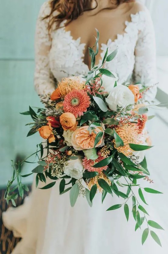 a catchy spring wedding bouquet with coral, yellow and orange blooms, berries and greenery is a lovely touch of color