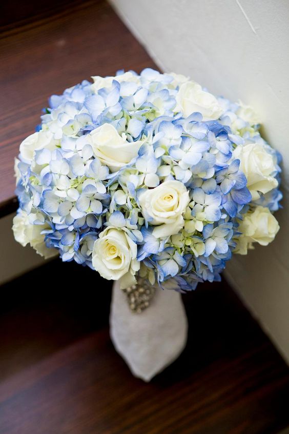 a catchy wedding bouquet of white roses and blue hydrangeas is a lovely idea for spring or summer