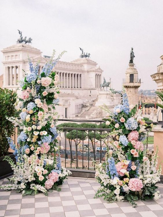 a charming wedding altar with blue and blush hydrangeas, blush roses and delphinium plus greenery and iconic Rome views