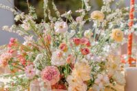 a cheerful wedding centerpiece of white, blush and pink and yellow blooms including carnations and peonies is a lovely idea for summer