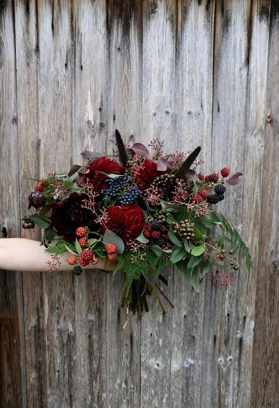 a chic Halloween bouquet with dark burgundy and red blooms, greenery and foliage and lots of berries