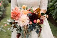 a chic fall wedding bouquet of coral, pink and burgundy dahlias, smaller and larger ones, some greenery, thistles and lisianthus