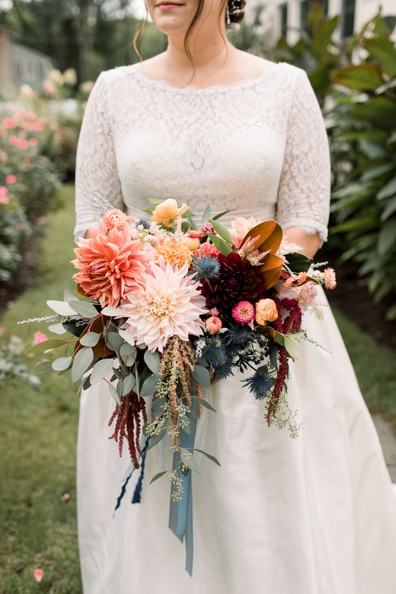 a chic fall wedding bouquet of coral, pink and burgundy dahlias, smaller and larger ones, some greenery, thistles and lisianthus