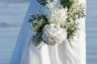 a chic wedding bouquet of white hydrangeas, baby’s breath and greenery for a coastal or beach wedding