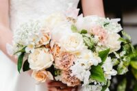 a classic and elegant wedding bouquet of white and blush roses, blush carnations, white hydrangeas, some leaves and fillers