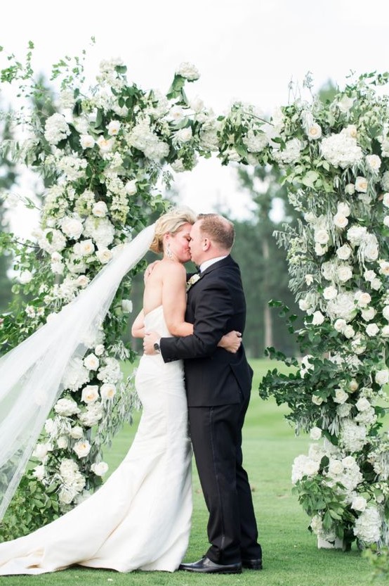 a classic greenery and white bloom wedding arch will work for any season and any wedding theme