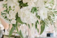 a classic tall wedding centerpiece of white roses and hydrangeas and greenery for a spring or summer wedding
