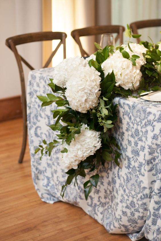 a classic wedding table runner of lush white hydrangeas and greenery is a cool idea for a rustic wedding, it looks stylish