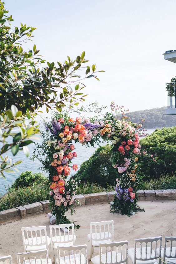 a colorful wedding arch decorated with purple, blush, yellow and white blooms including paonies and roses plus greenery