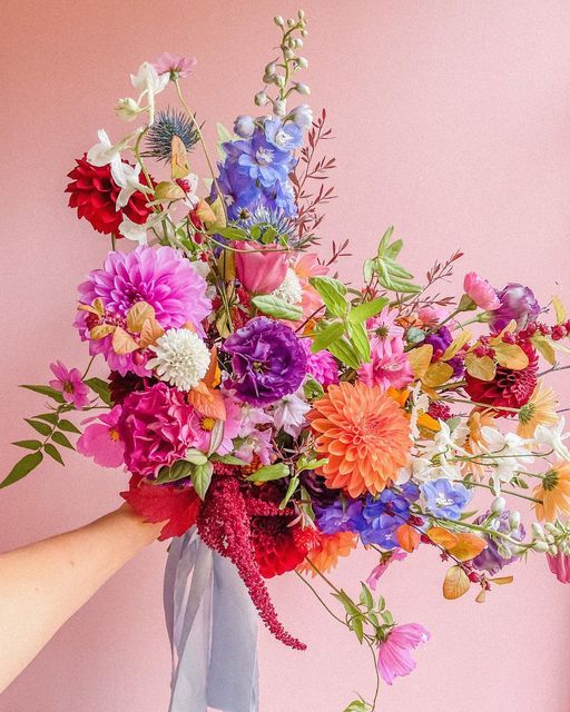 a colorful wedding bouquet of pink and orange dahlias, blue blooms, pink and hot pink carnations, greenery and thistles