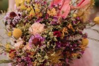 a colorful wedding bouquet of pink waxflowers, blush carnations, bold yellow blooms and billy balls for a bright boho wedding