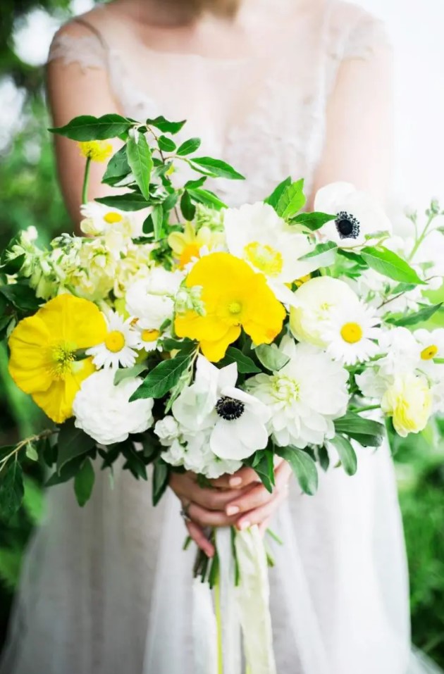 a colorful wedding bouquet of white anemones and dahlias, yellow poppies and chamomiles, greenery for a summer wedding