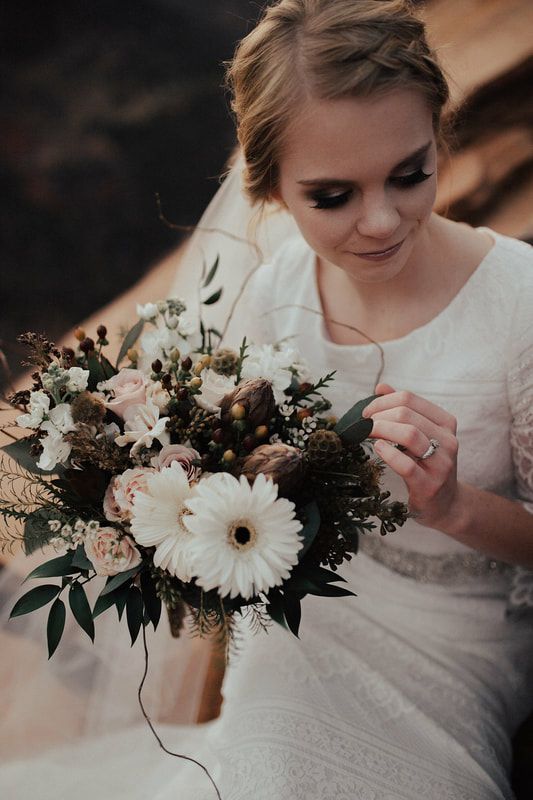a cool neutral and pastel wedding bouquet of white gerberas, blush roses, white blooms, seed pods, waxflowers, greenery and twigs