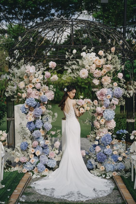 a creative wedding arch made using a rotonda and blush and blue hydnrageas, roses and dahlias looks very delicate and chic