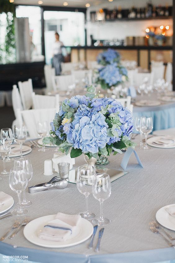 a cute and cool wedding centerpiece of blue hydrangeas, greenery and neutral blooms is a stylish idea for spring and summer