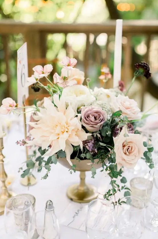 a decadent fall wedding centerpiece with blush dahlias, lilac roses, white peony roses, some greenery and fillers